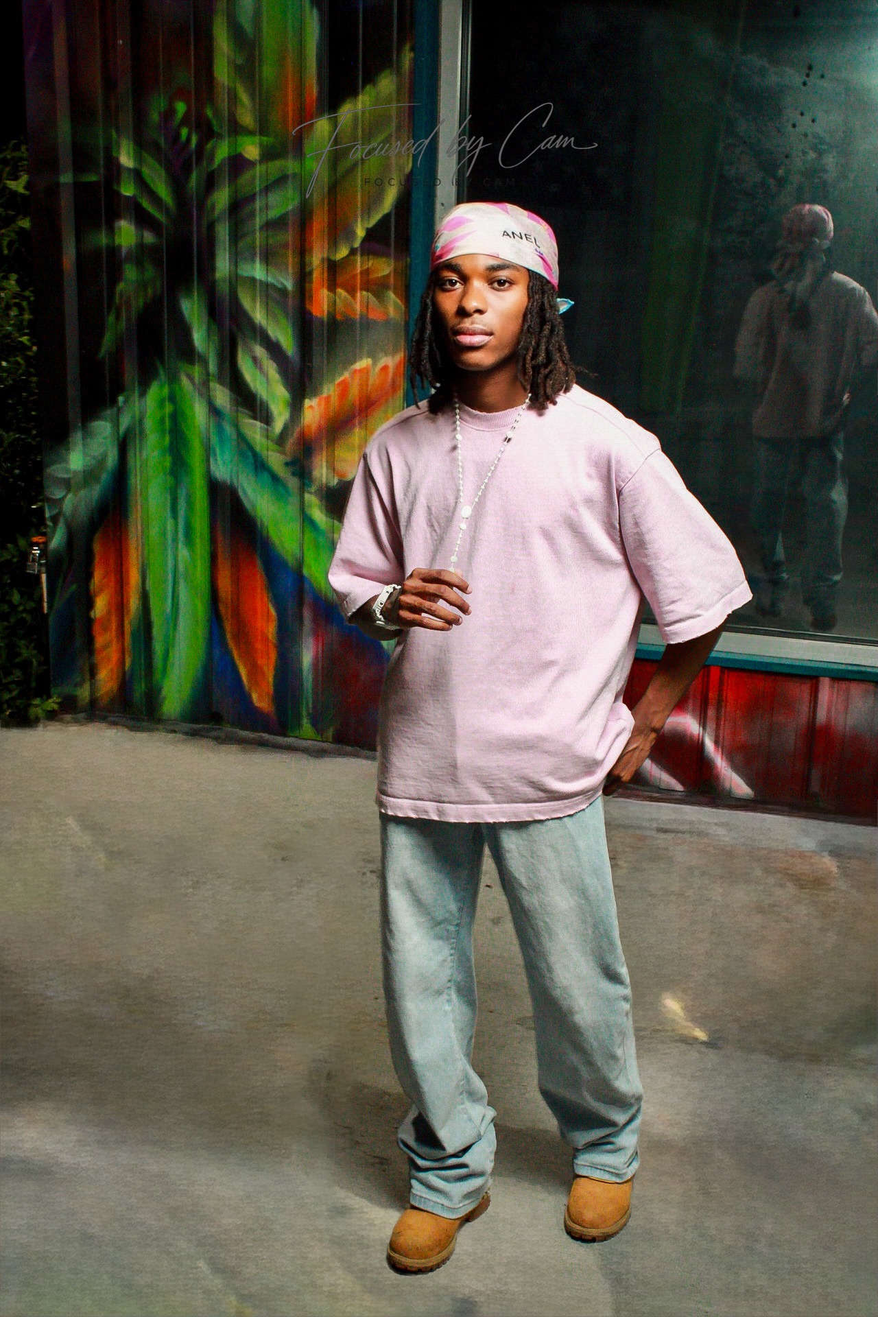 Male portrait wearing pink in front of a colorful mural